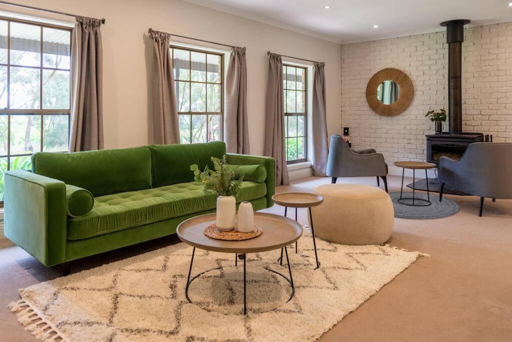 a living room with a green couch and a table at Furche Barossa Vineyard Family Stay 