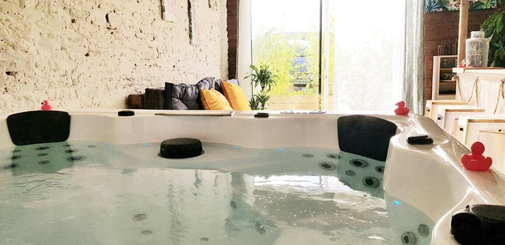 uma banheira cheia de água num quarto em Gîte Evanez Mont-saint-Michel jacuzzi intérieur privatif illimité em Pontorson