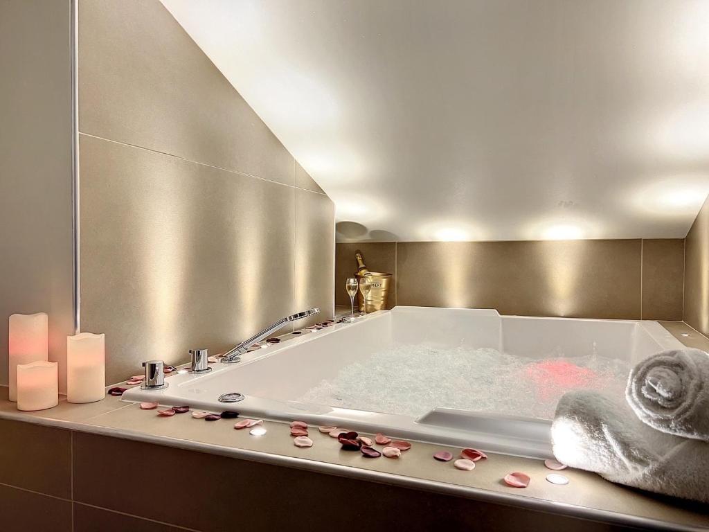 uma casa de banho com uma banheira e um espelho. em Cocon Blanc câlin - Jacuzzi privatif - Love Room à Saint Etienne em Saint-Étienne