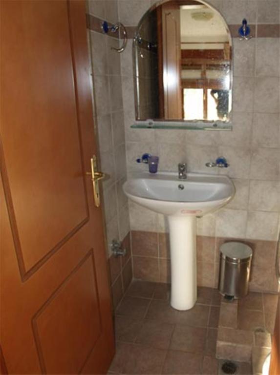 a bathroom with a sink and a mirror and a door at Hotel Kosmas in Sarti
