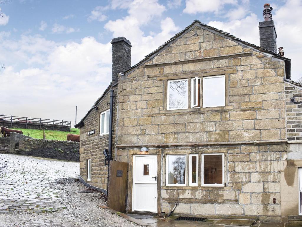 an old stone house with a white door at Newlands Farm Cottage Halifax in Luddenden Foot