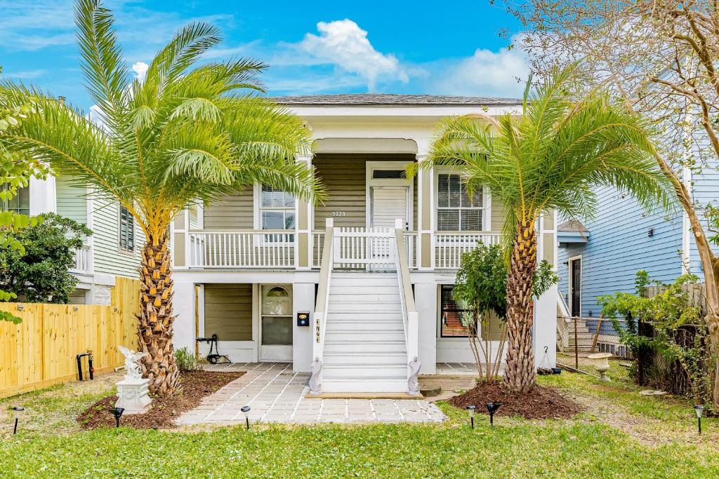a white house with palm trees in front of it at Ocean Waves in Galveston