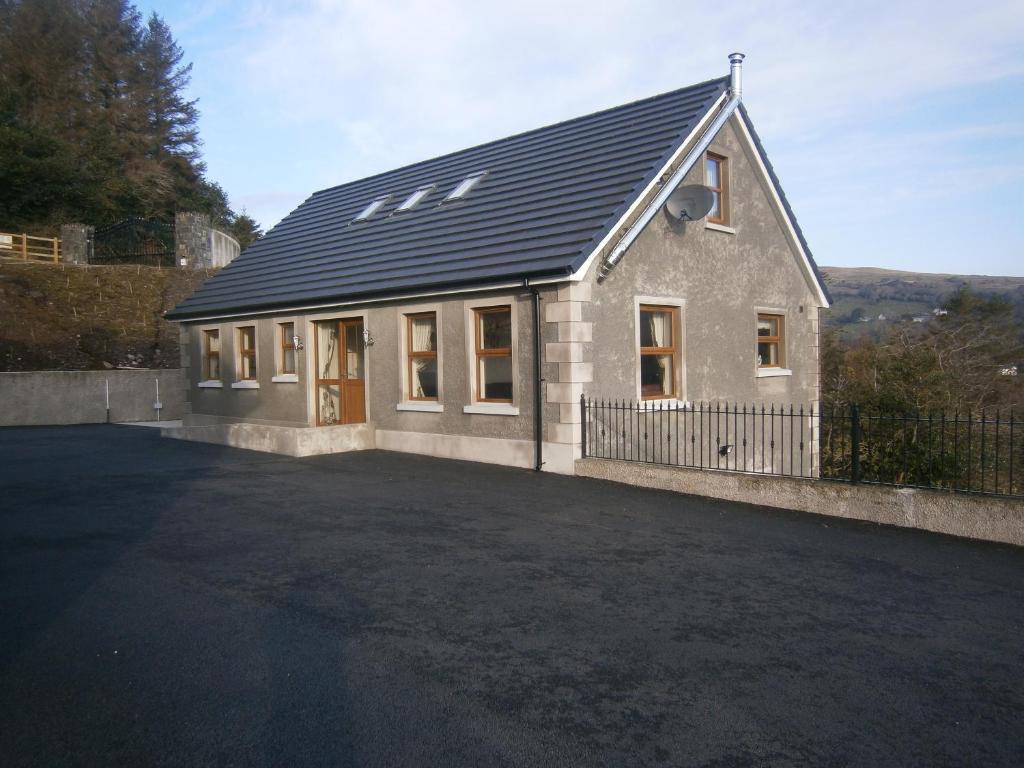 a house with a black roof with a driveway at Glendun Self Catering in Cushendall