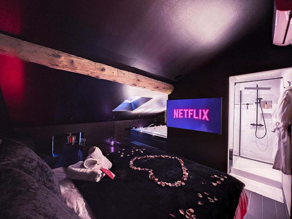 1 dormitorio con 1 cama con un cartel de netflix en la pared en Suite Privative Rouge baiser - Spa & Jacuzzi - Love Room à Saint Etienne en Saint-Étienne