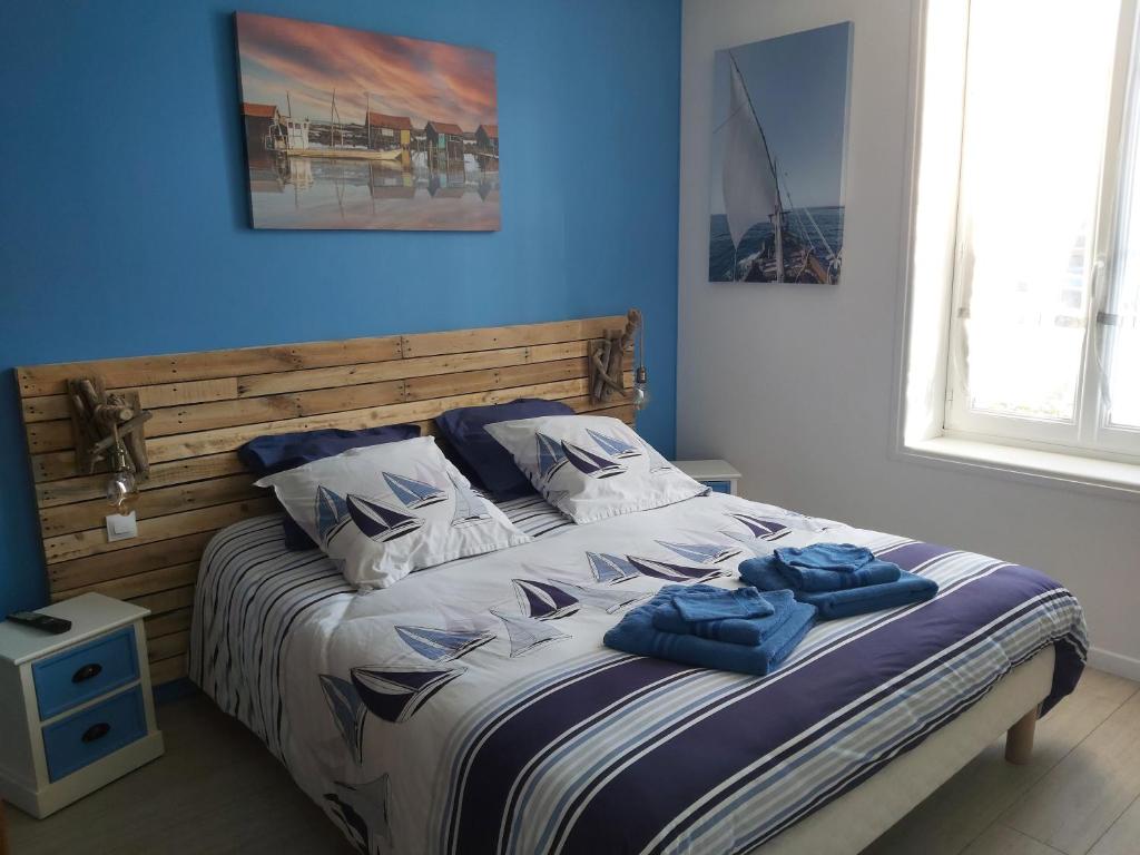 Una cama con dos toallas azules encima. en "chez Nat", en Chaillevette