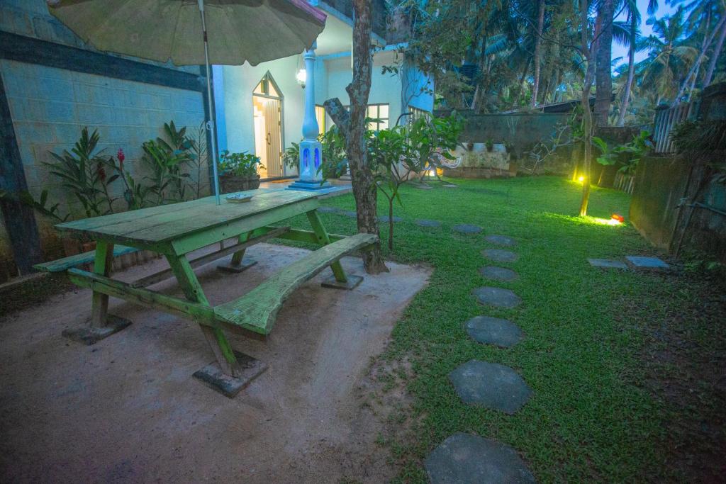 a picnic table with an umbrella in a yard at Percy Residence in Unawatuna