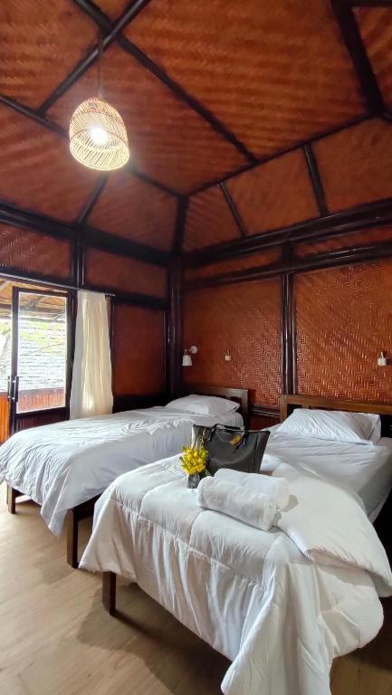 a bedroom with two beds with white sheets at Kelimutu Paradiso Resort in Kelimutu