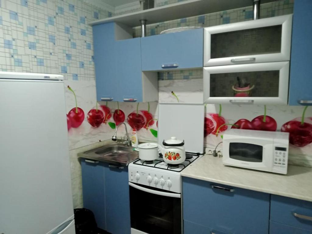 Una cocina con estufa y microondas y manzanas rojas. en Квартиры, en Shchūchīnsk