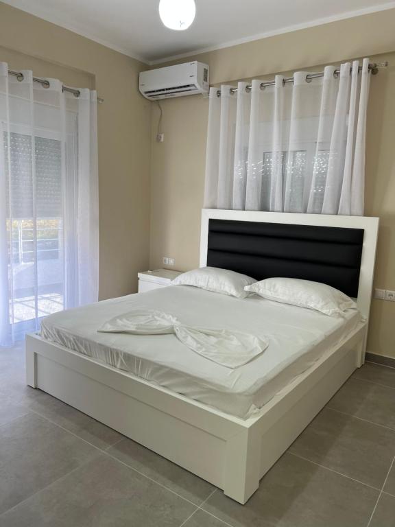 una camera da letto con un grande letto bianco con lenzuola e cuscini bianchi di Harmony Apartments a Sarandë