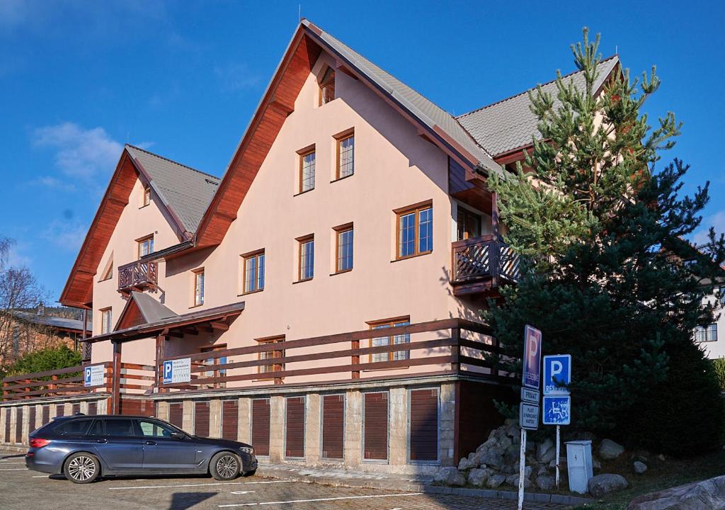 une maison avec une voiture garée devant elle dans l'établissement Slunný a vzdušný Apartmán Astra - by Relax Harrachov, à Harrachov