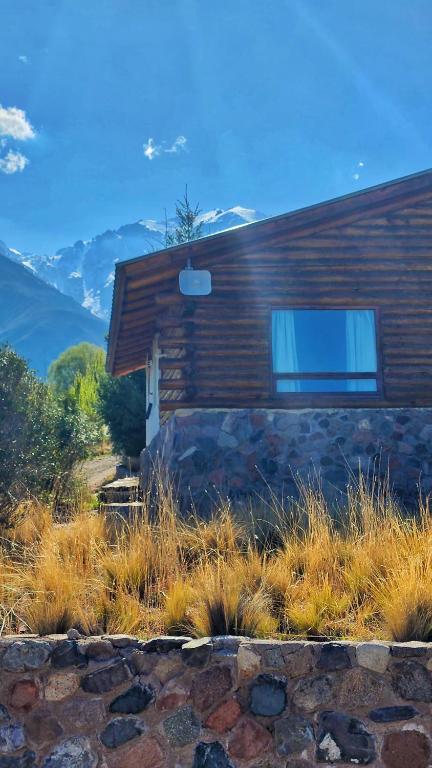 a log cabin with mountains in the background at Cabañas Mirador Azul, Potrerillos in Potrerillos