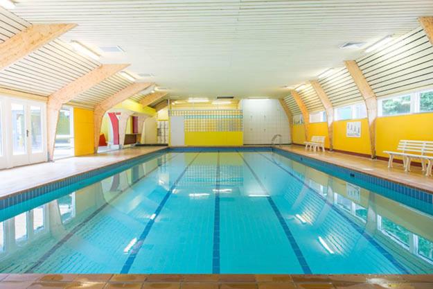 a large swimming pool with blue water in a building at Chalet 46 Casa Fantasia in Durbuy