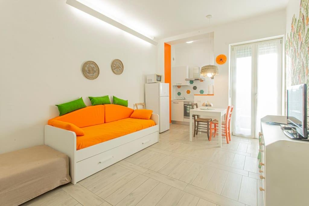 een oranje bed in een witte kamer met een keuken bij [Stellantis-Alpitour] Casa Tucano in Turijn
