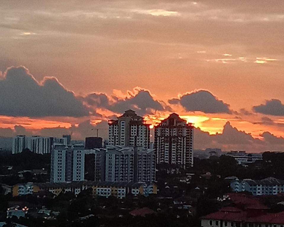 een zonsondergang boven een stad met hoge gebouwen bij A room in Aparnt Sri Impian in Johor Bahru