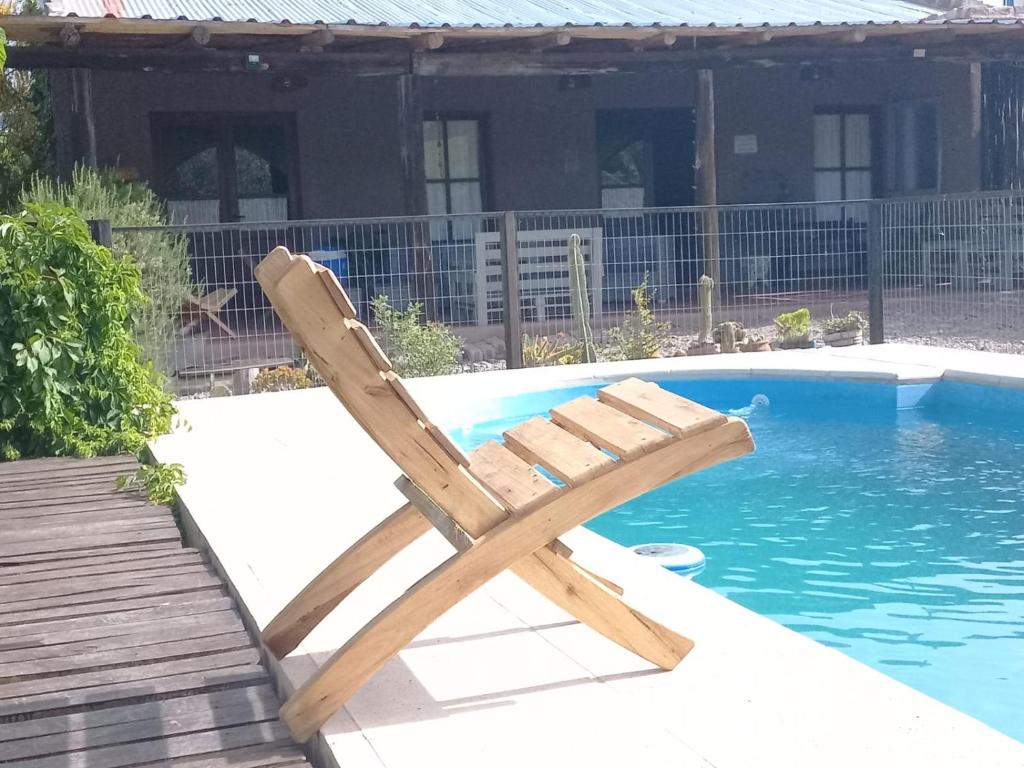 una silla de madera junto a la piscina en Cazasanta en Mendoza