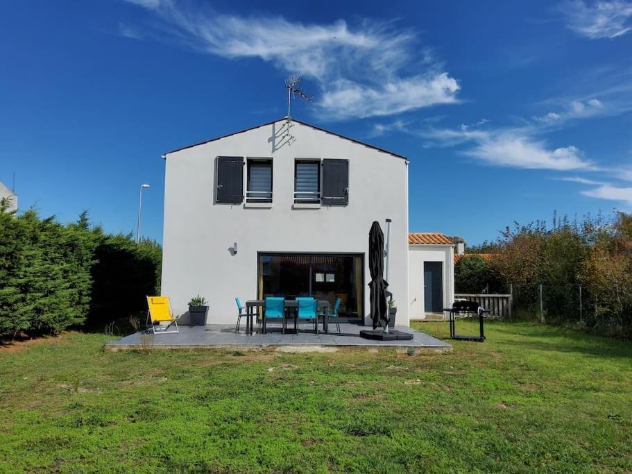 a white house with a table and chairs in a yard at 003 QUIN - Maison du Maine in Grand-Village-Plage