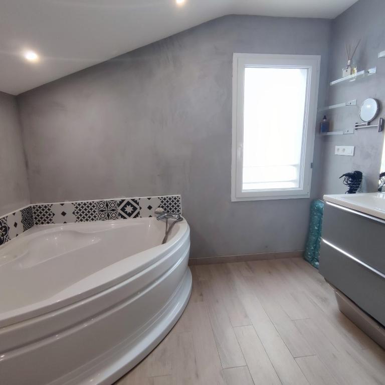 biała łazienka z wanną i oknem w obiekcie Maison du Maine w mieście Grand-Village-Plage