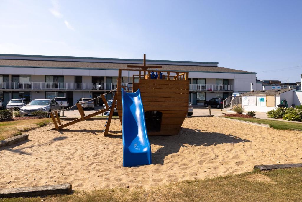 un parque infantil con un tobogán azul en la arena en John Yancey Oceanfront Inn, en Kill Devil Hills