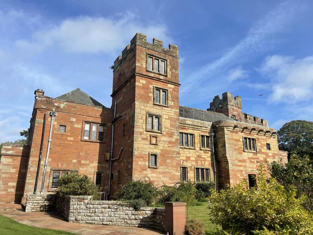 an old brick building with a tower on top at Dalston Hall in Carlisle