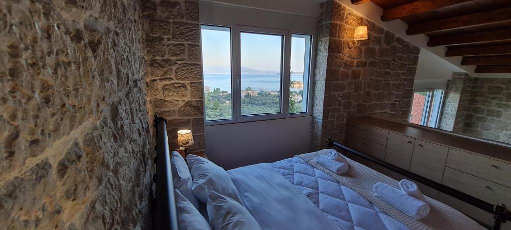 1 dormitorio con 1 cama en una habitación con ventanas en Πέτρα, Ελιά και Λεβάντα en Tolo