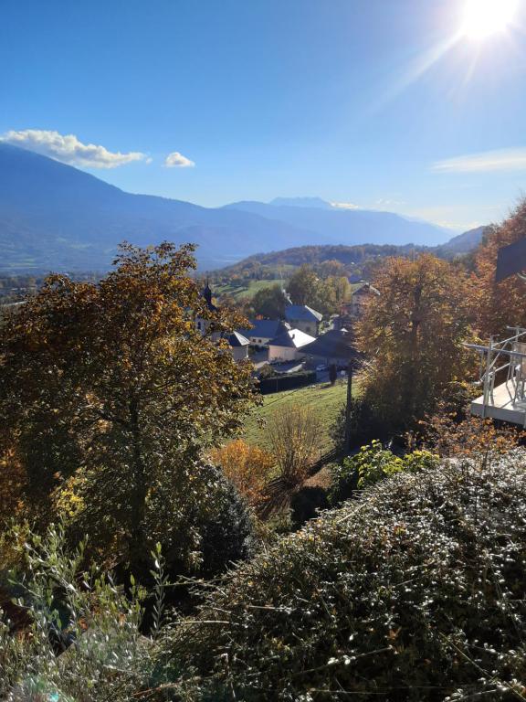 uma vista para uma colina com árvores e montanhas ao fundo em Gite de la tour em Plancherine