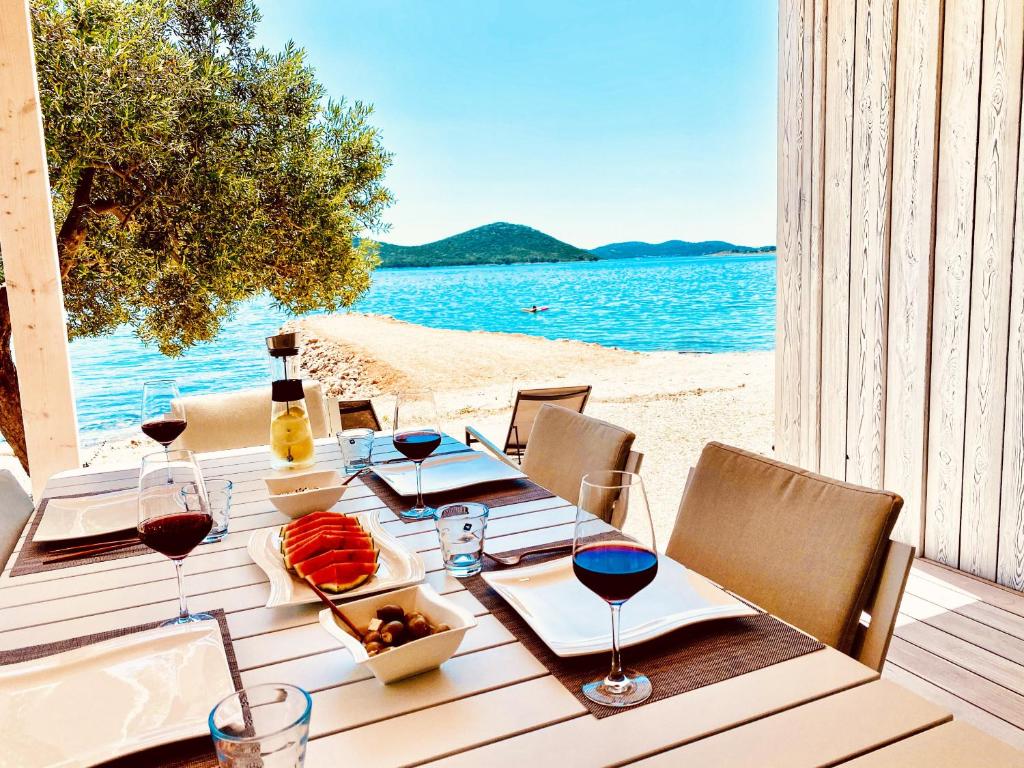 uma mesa com copos de vinho e comida numa praia em BUQEZ ECO RESORT - Beach Villa 28 - Directly by beach em Drage