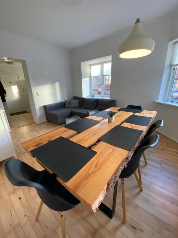 uma sala de estar com uma grande mesa de madeira e cadeiras em Central Ground Floor Apartment with Parking em Aarhus