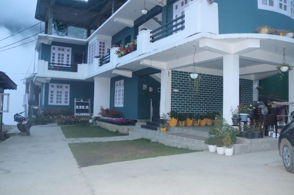 a blue and white house with a car parked in front at Monshing Homestay - Elevate your travel experience in Bomdila