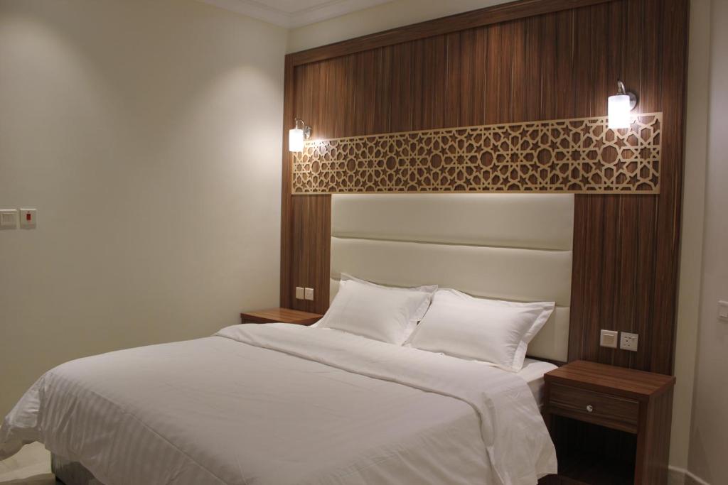 a bedroom with a white bed with a wooden headboard at التميز الراقي - الفيصلية in Jeddah