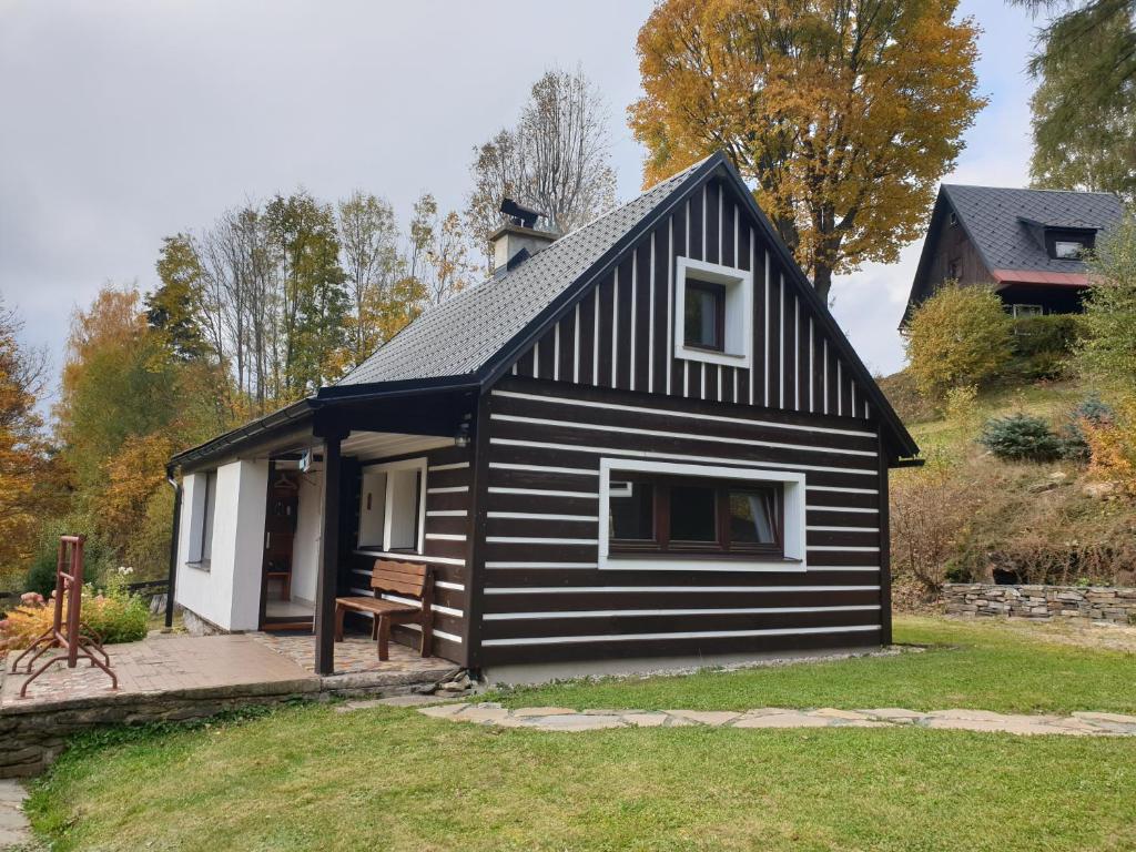 a black and white house with a bench in a yard at horská chata Cecilie in Olešnice v Orlických horách