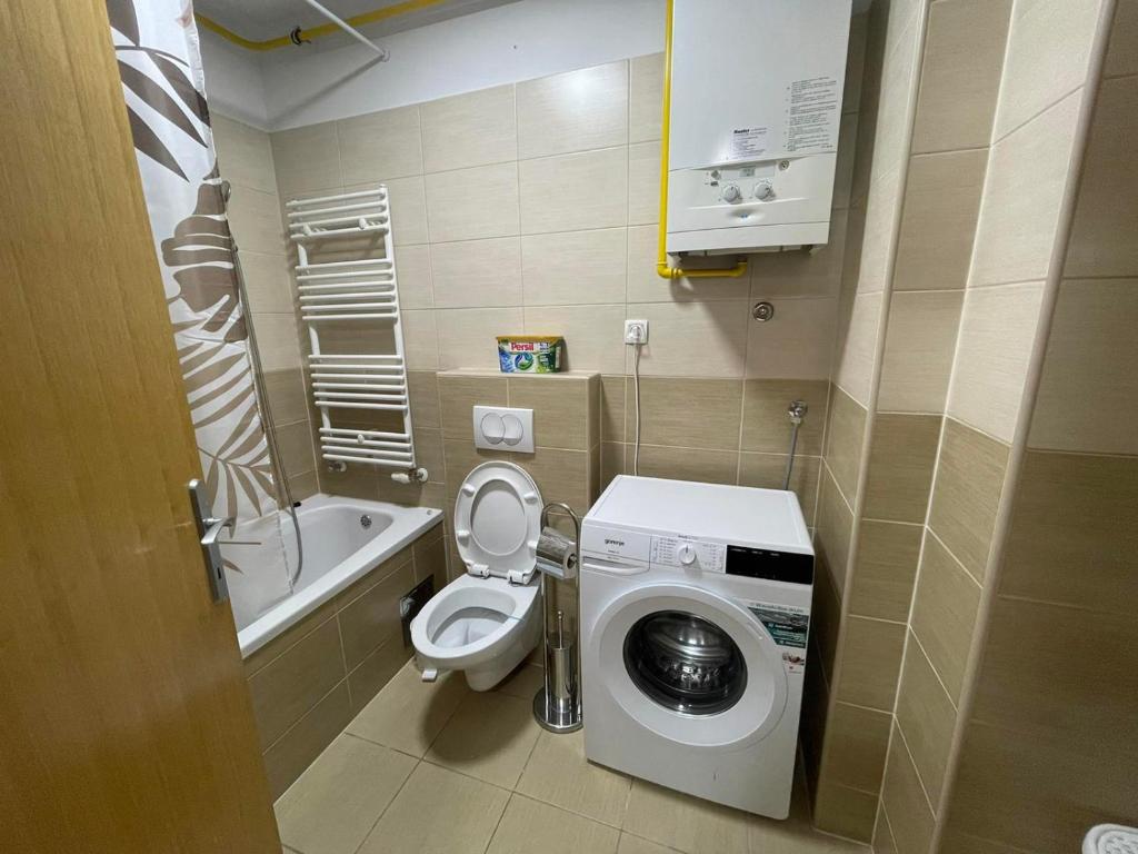 a small bathroom with a toilet and a washing machine at Apartmani Marčetić in Slavonski Brod