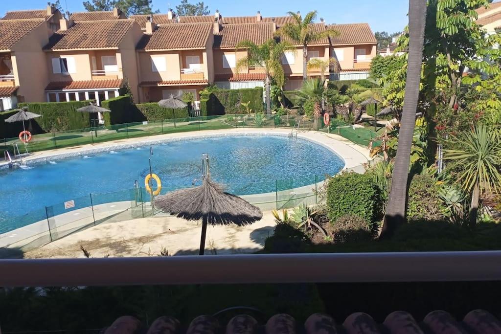 a view of a swimming pool with an umbrella at Adosado playa Islantilla campo de golf in Huelva