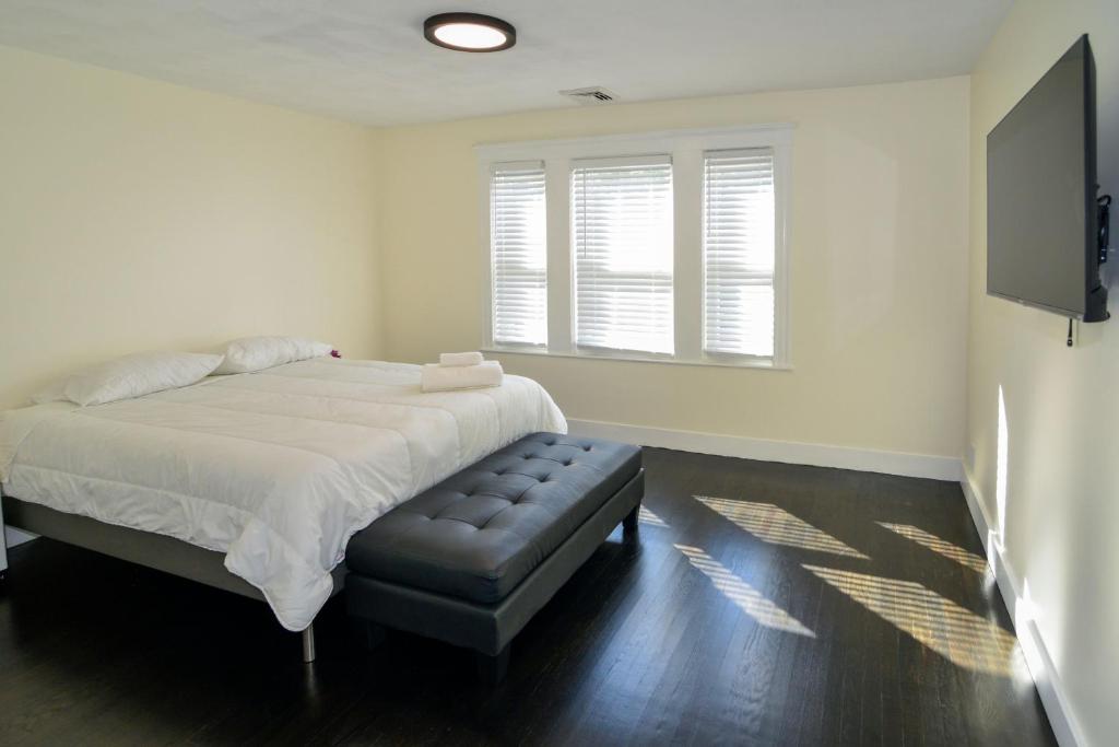 a white bedroom with a bed and a stool at Modern Two Bedroom Condo - Boston in Stoneham