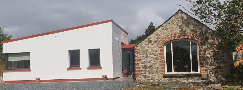 Casa blanca de ladrillo con un edificio de piedra en The Haggard Self Catering Accommodation, en Castleblayney