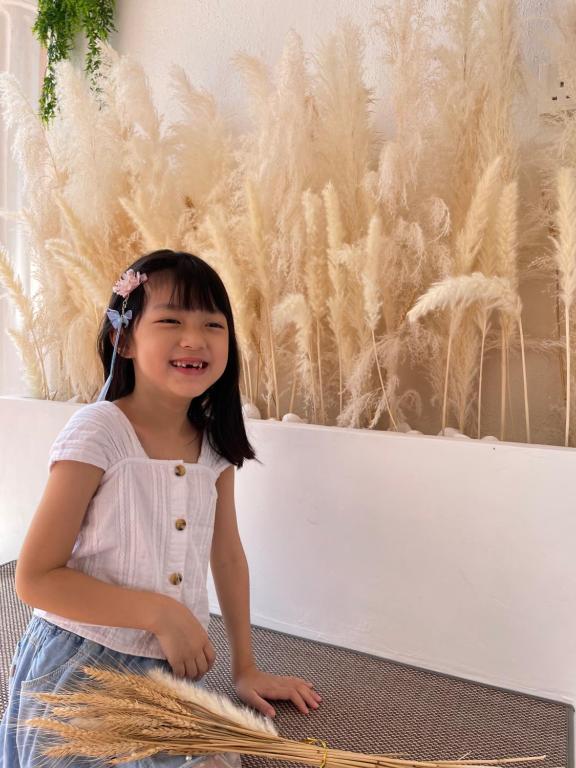 a little girl sitting in front of a wall at QV Residence Langkawi - Jacuzzi, BBQ, & Steamboat in Kuah