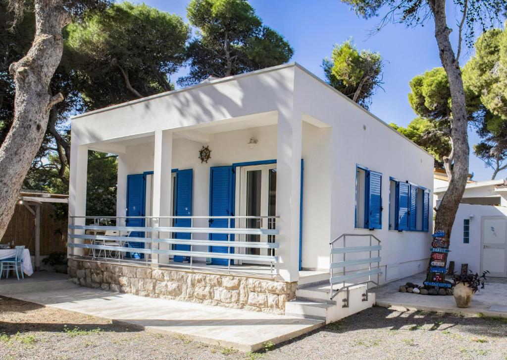 uma casa branca com persianas azuis e uma árvore em Casa Cristina em Porto Pino