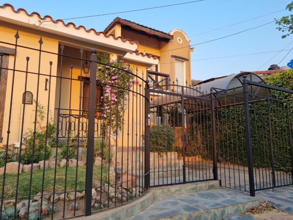 uma cerca preta em frente a uma casa amarela em Hostal las Rosas em Salta