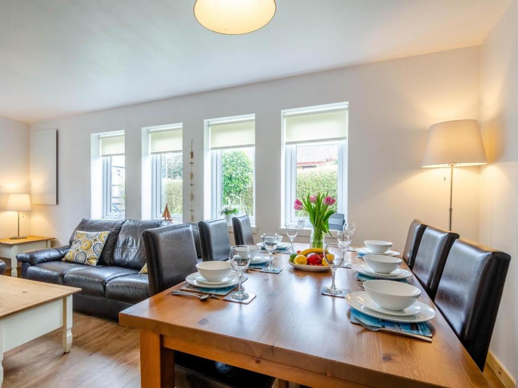 a dining room with a table and chairs and a couch at Cosy 3 bedroom home in centre of Brodick in Brodick