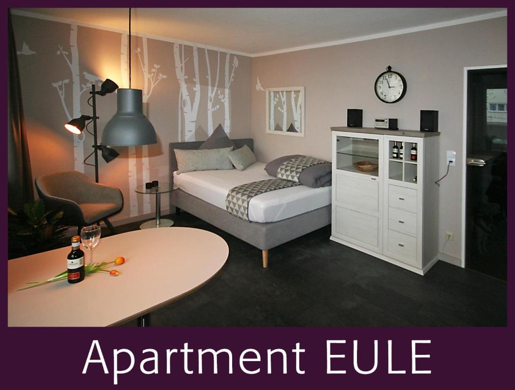 ein Schlafzimmer mit einem Bett und einem Tisch sowie ein Zimmer mit einer Suite in der Unterkunft Apartment EULE - Gute-Nacht-Braunschweig in Braunschweig