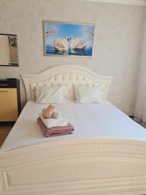 Una cama blanca con una toalla encima. en Мини гостиница в центре en Uralsk