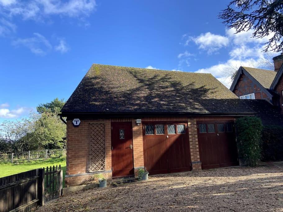 a small house with red doors and a fence at The Little Gable in Wavendon