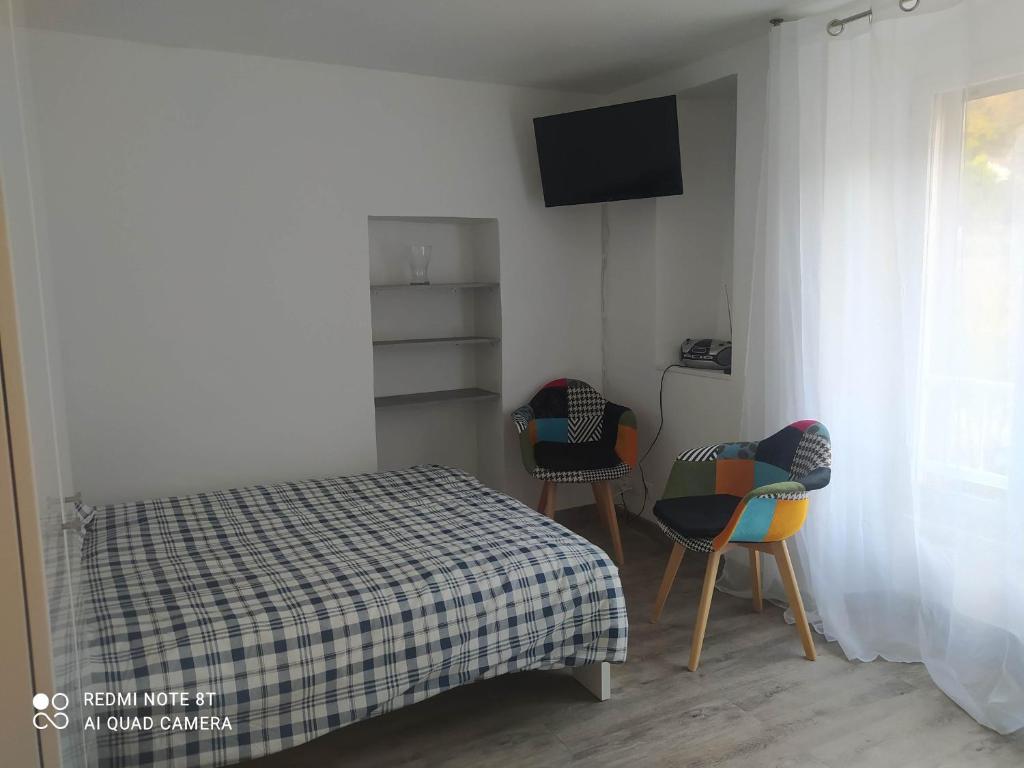 - une petite chambre avec un lit et deux chaises dans l'établissement Joli studio au centre d'Uriage, à Vaulnaveys-le-Haut