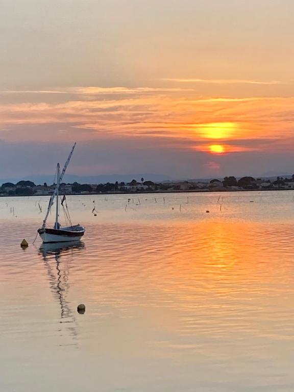 un bateau assis dans l'eau au coucher du soleil dans l'établissement L'Estanque l'étang des vacances parking climatisation, à Sète