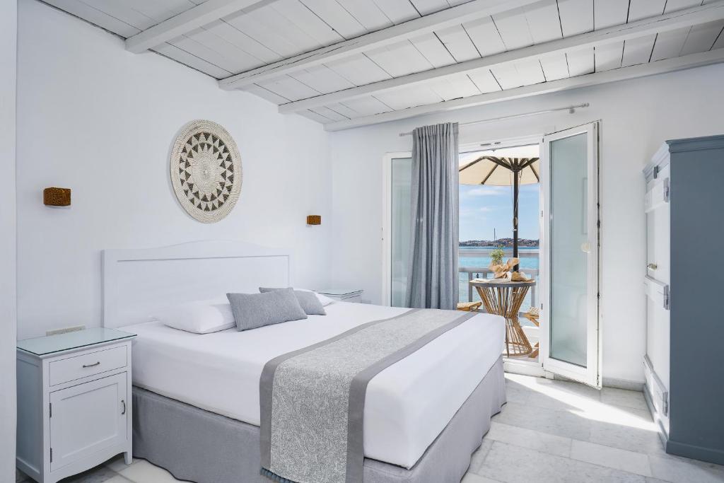 a white bedroom with a bed and a balcony at Kalergis Studios in Naxos Chora