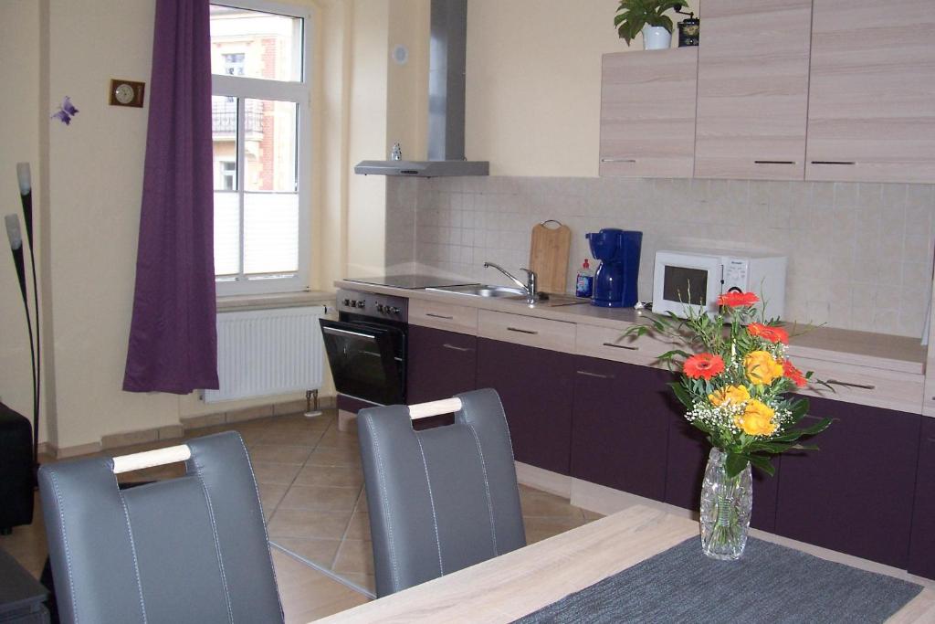 a kitchen with a table and chairs and a vase of flowers at Ferienwohnung am Schunckpark in Dresden