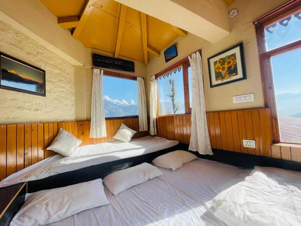 2 camas en una habitación con 2 ventanas en Neer Stays en Munsyari