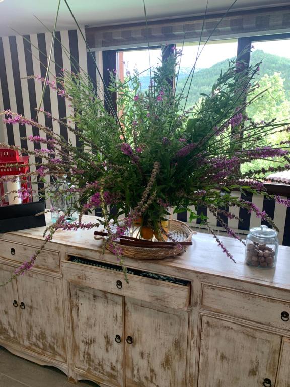 un jarrón de flores sobre un armario de madera en Los acebos el atico en Gallejones