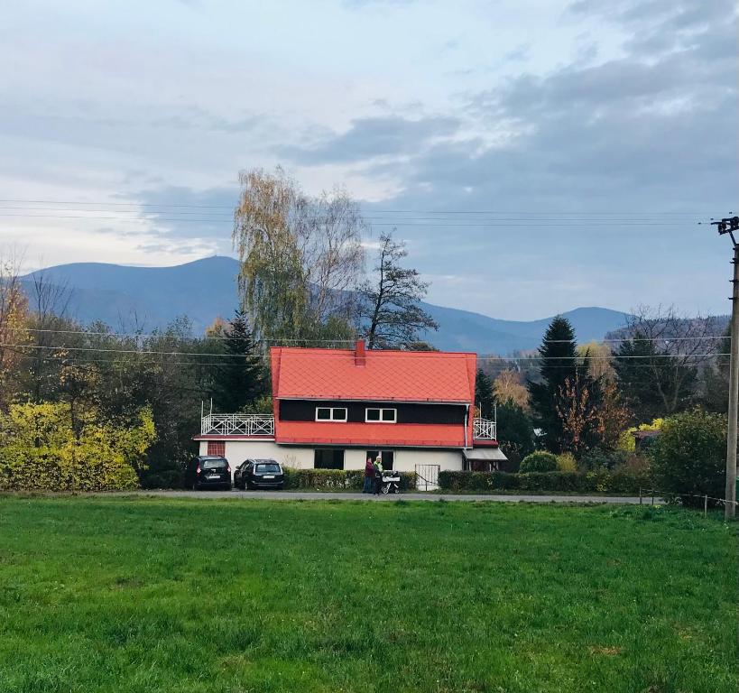 ein Haus mit rotem Dach und zwei Autos auf einem Feld in der Unterkunft Chata u Chrobáčků na Čeladné in Čeladná