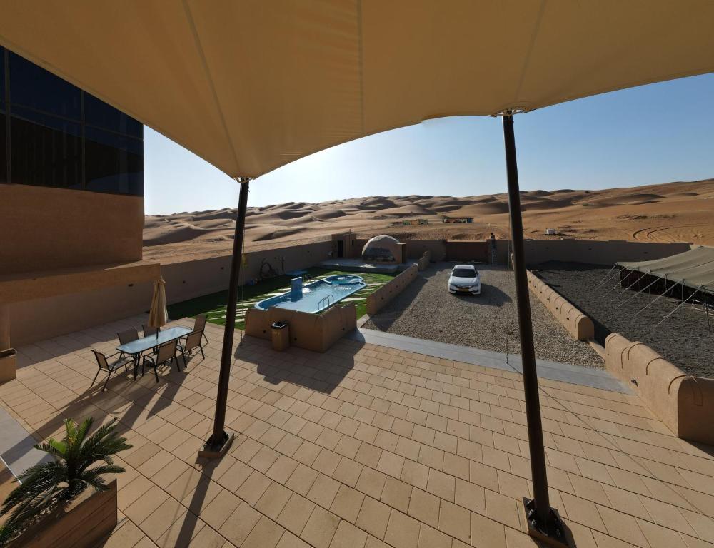 an outdoor patio with an umbrella in the desert at Sand House ساند هاوس in Al Raka