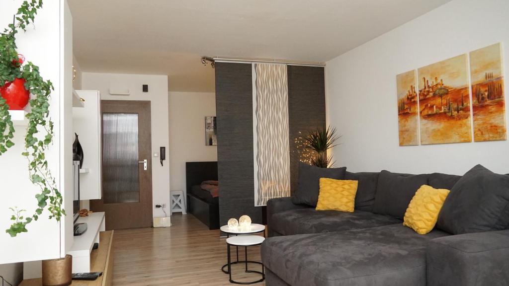 ein Wohnzimmer mit einem grauen Sofa und gelben Kissen in der Unterkunft Gemütliches Apartment in Bad Berneck in Bad Berneck im Fichtelgebirge